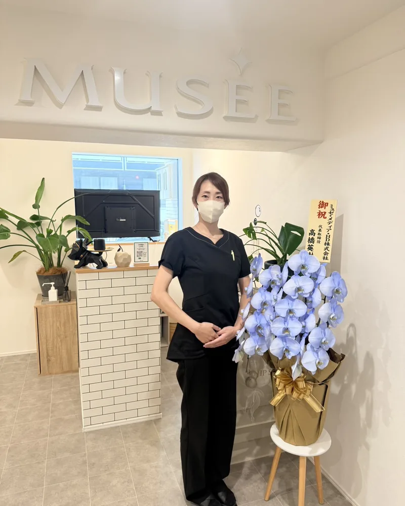 MUSEE の文字が掛かった白い受付と、青い胡蝶蘭