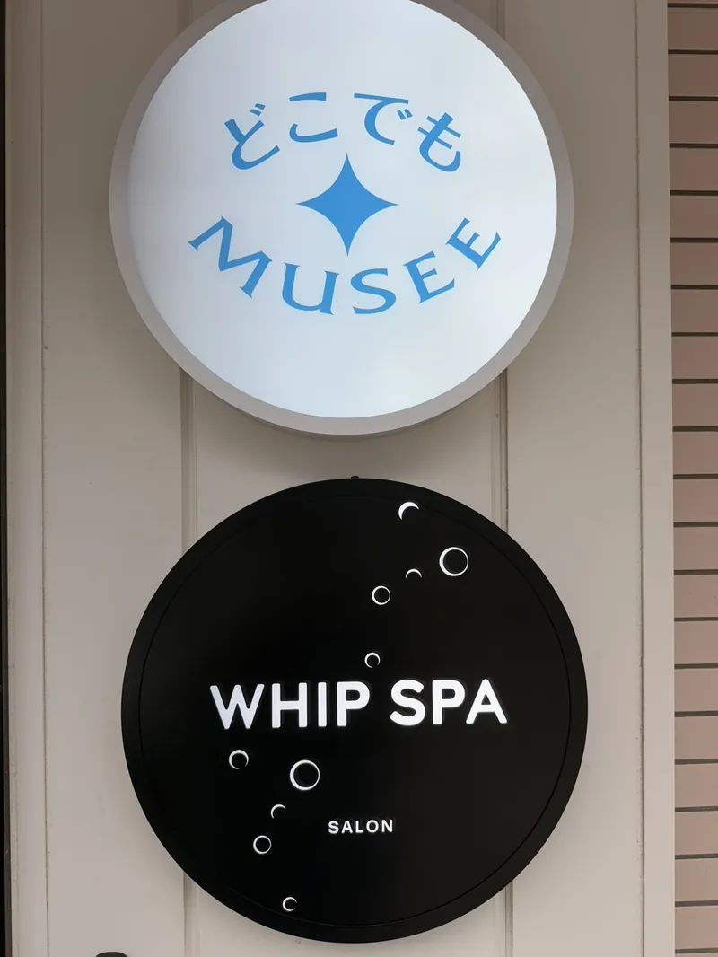 入口の丸い看板。上がどこでもMUSEE、下が黒いWHIP SPA